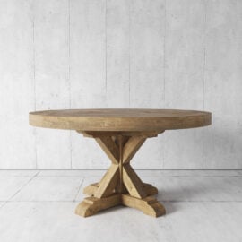 A round wooden table with a crossed-leg base is set against a concrete wall and floor background.