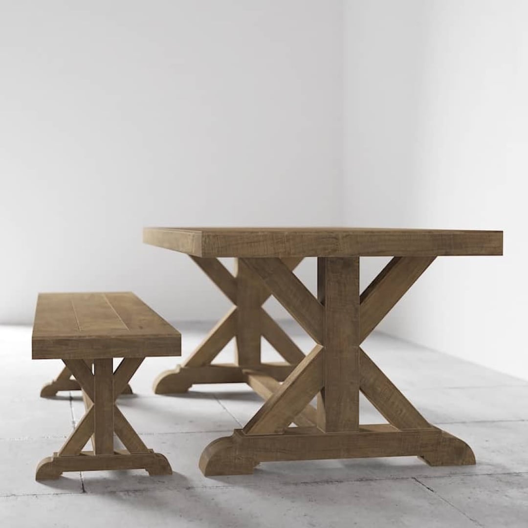 Madera Cross Base 78, Table and Bench0003 A Madera Dining Table with an X-shaped base and the matching Madera Dining Bench are placed in a minimalistic, empty room with white walls and a light-colored floor.