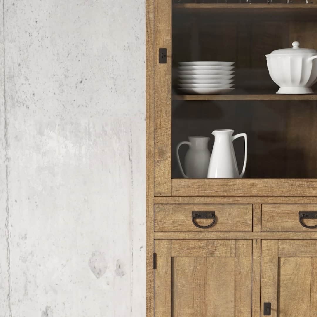 Urban Woodcraft 36 Riverbend Display Consol - Natural (3) The Riverbend 36" Display Cabinet, featuring a glass door, elegantly showcases white dishes, a pitcher, and a covered dish against the backdrop of a textured concrete wall.