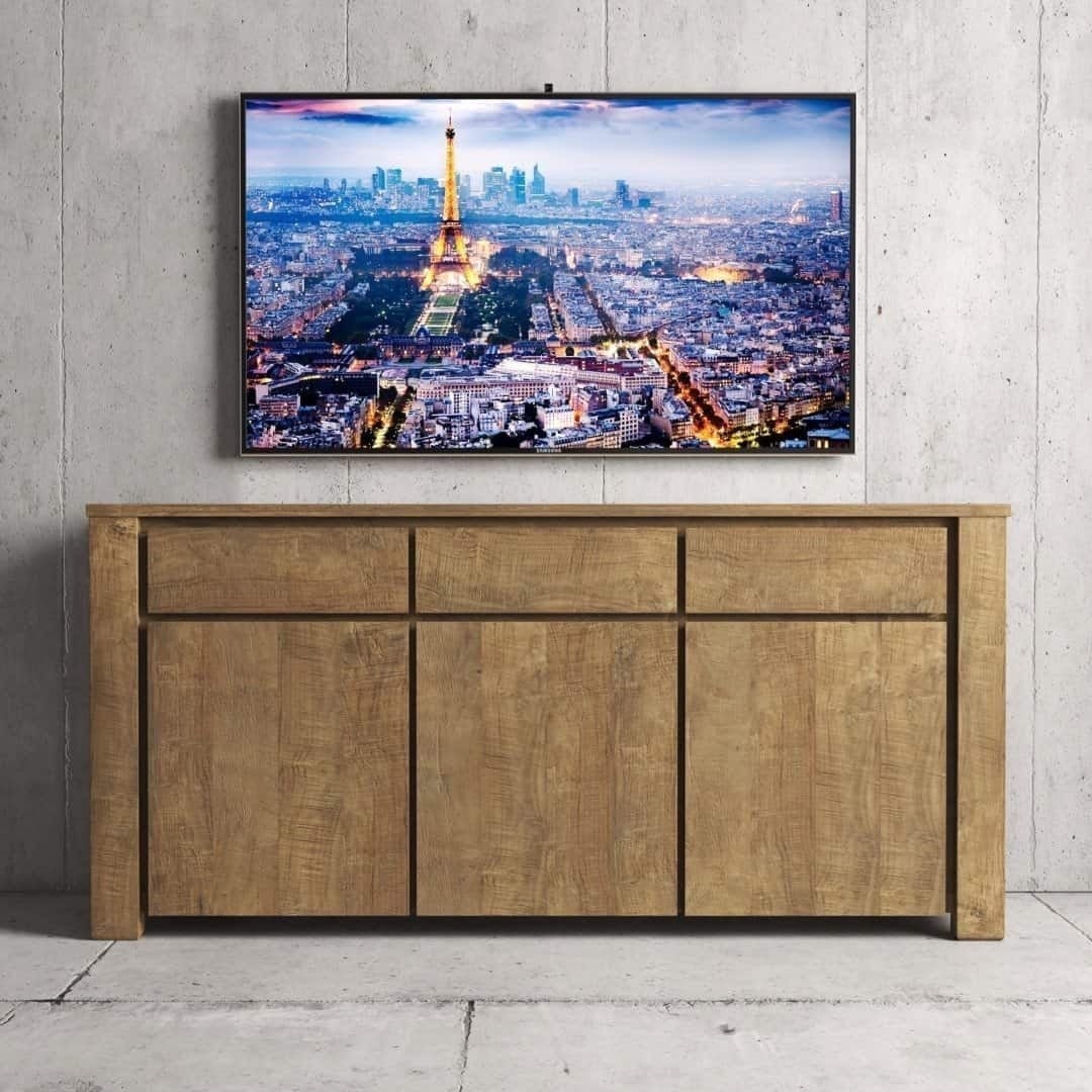 Urban Woodcraft 75 Teca Dining Buffet - Natural TV The Teca Dining Buffet, featuring drawers and cabinets, is placed against a concrete wall. Above it, a flat-screen TV showing a cityscape with the Eiffel Tower stands mounted.