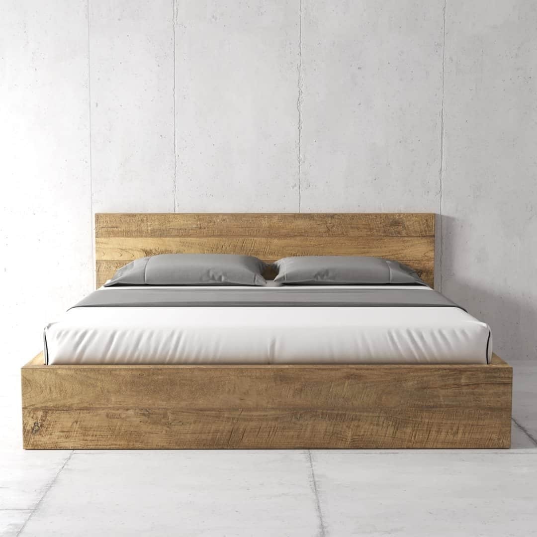 Urban Woodcraft Lugano Bed - Natural (5) The Lugano Bed, a wooden bed frame with a headboard, is adorned with neatly made white sheets and two gray pillows, set against a plain, light-colored wall.