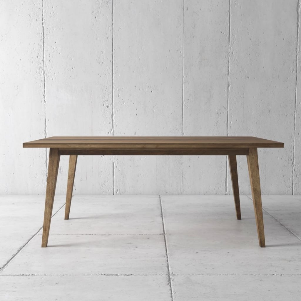 The Circa Dining Table (Natural) with tapered legs stands on a white tiled floor against a plain gray concrete wall.