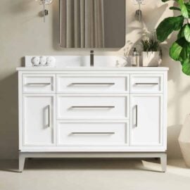 A Barrington 48" Single Sink Bathroom Vanity in white, featuring multiple drawers and a sink, is topped with rolled towels and a soap dispenser. A rectangular mirror and a potted plant are also visible.