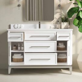 The Barrington 48" Single Sink Bathroom Vanity is a white piece featuring a mirror, various drawers, and cabinets. It's elegantly decorated with rolled towels, toiletries, wicker baskets, and has a potted plant on the side.