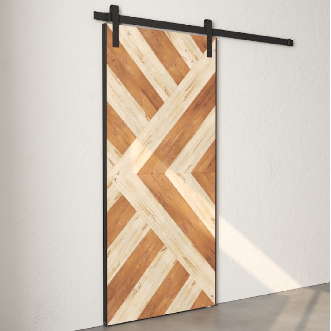The Lumina Reclaimed Wood Barn Door - White features a stunning geometric, diagonal wood pattern in light and dark tones, mounted on a sleek black metal track against a crisp white wall.