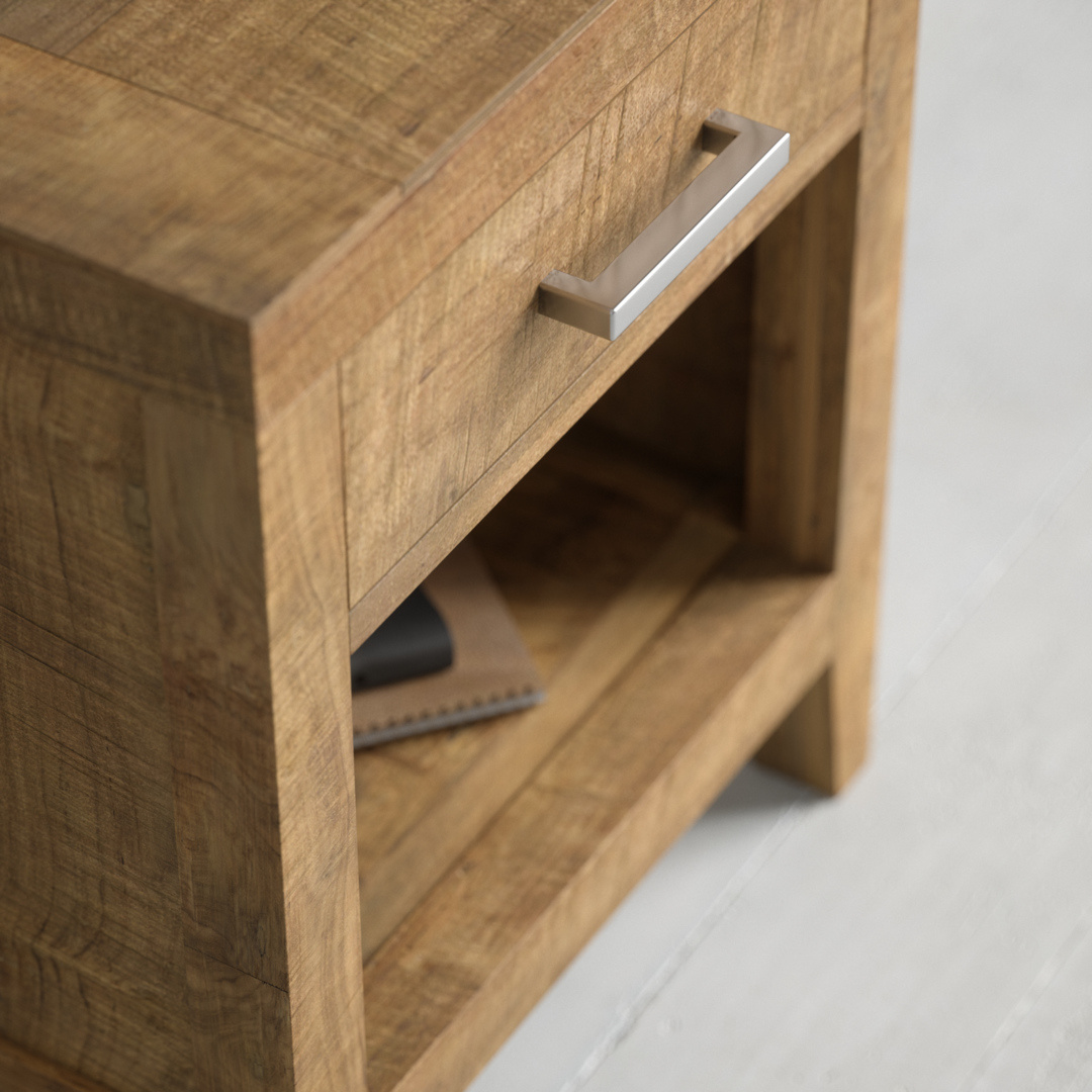 Riviera Nightstand - 2 Close-up of the Riviera Nightstand featuring a wooden design with a silver handle on the drawer and an open shelf below, holding a notebook and a black object.