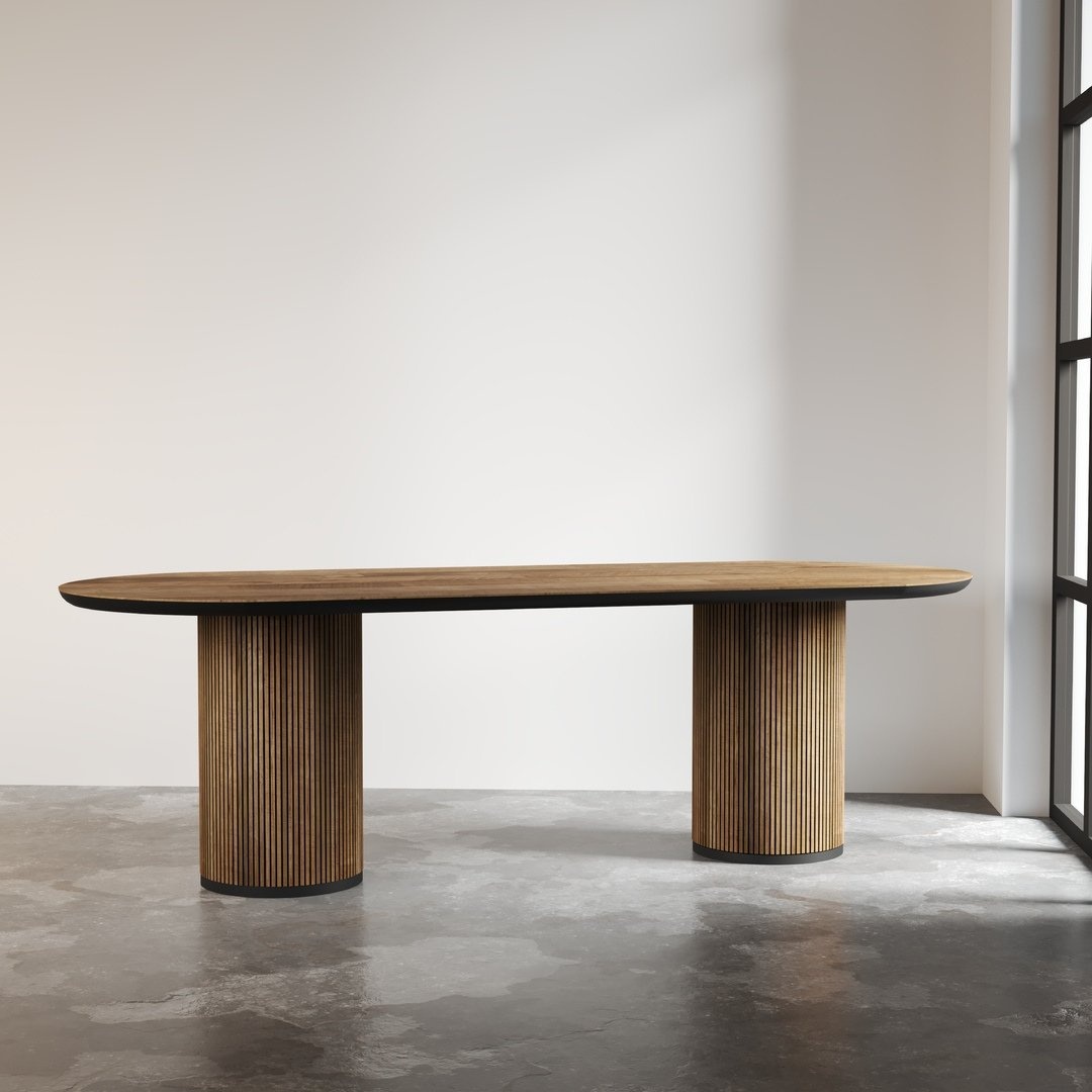 11-2.jpg The Bolivar Oval Dining Table, featuring a modern wooden design with grooved cylindrical legs, stands on a concrete floor in a minimalist room with a large window on the right.