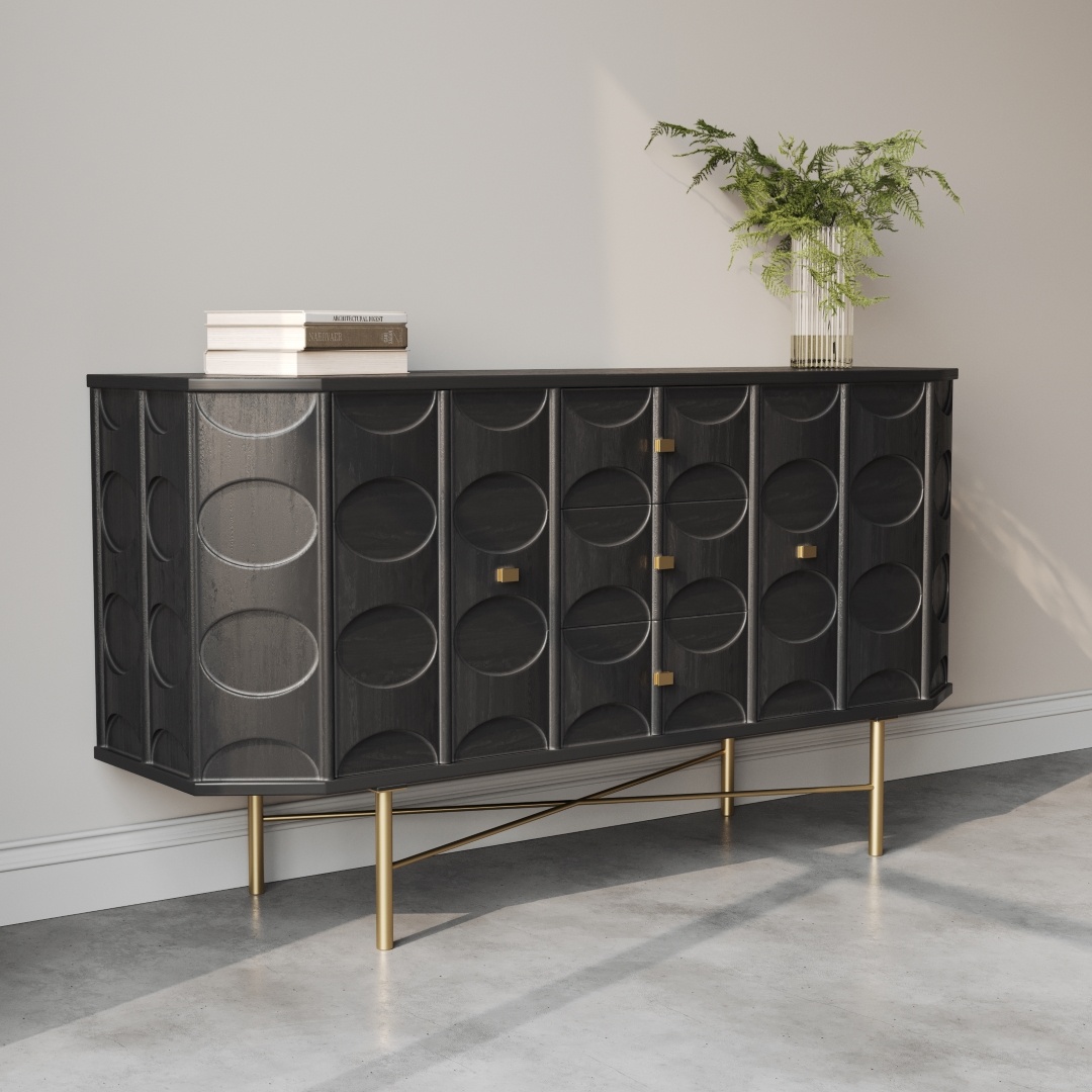 Alba 60 Side Cabinet-d The Alba 60" Sideboard, featuring a black finish with a circular pattern design, gold handles, and gold legs, stands against a light-colored wall. A small stack of books and a plant in a white pot are placed on top.