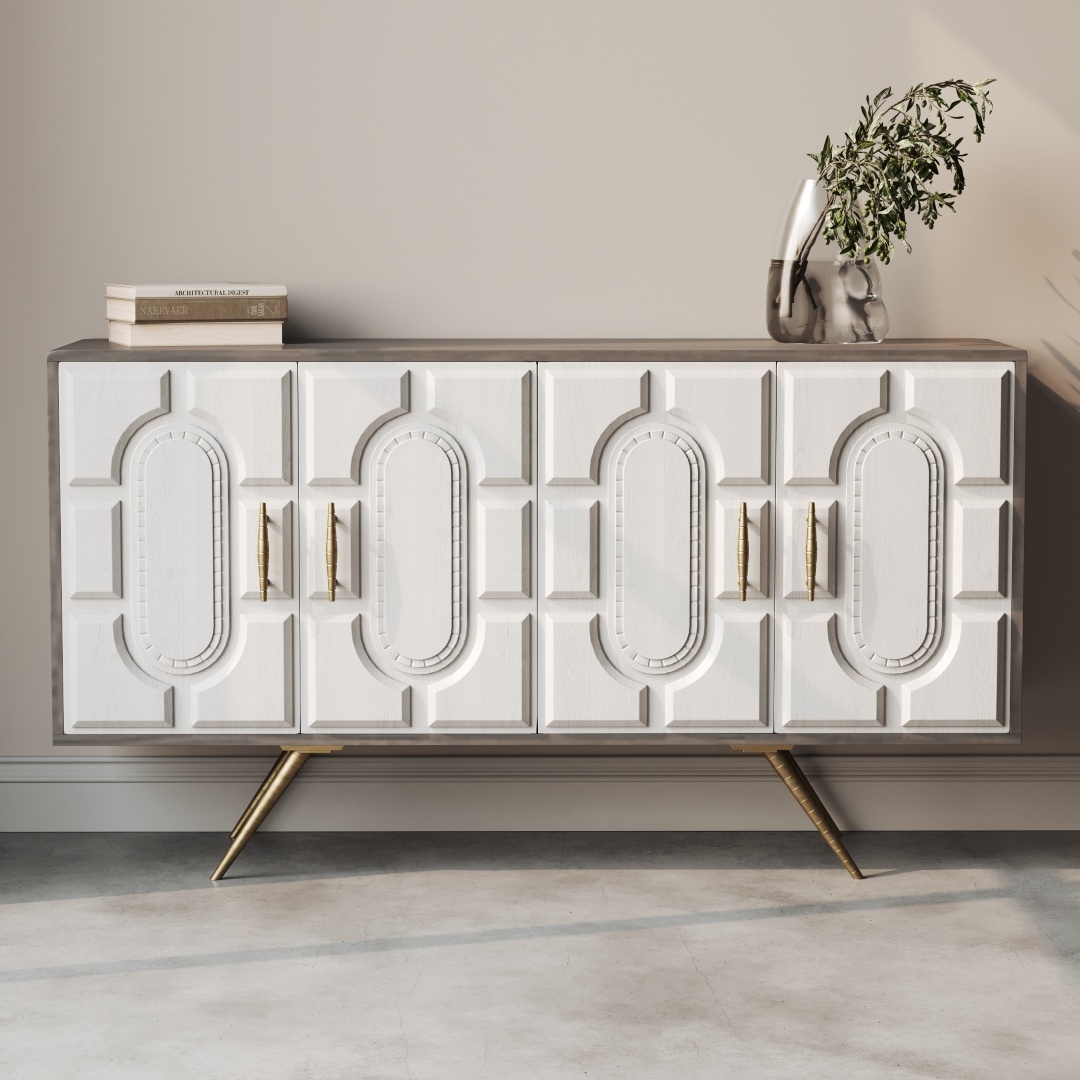 Lugo 60 Side Cabinet-a The Lugo 60" Sideboard, featuring intricate white paneling, elegant gold handles, and tapered legs, is elegantly positioned against a beige wall and adorned with a vase of greenery and stacked books.
