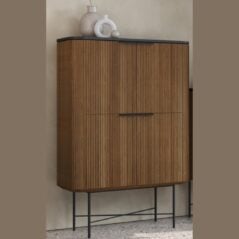 The Osaka Tall Display Cabinet features vertical grooves, black metal handles, and black metal legs. Decorative white vases are artfully placed on top.