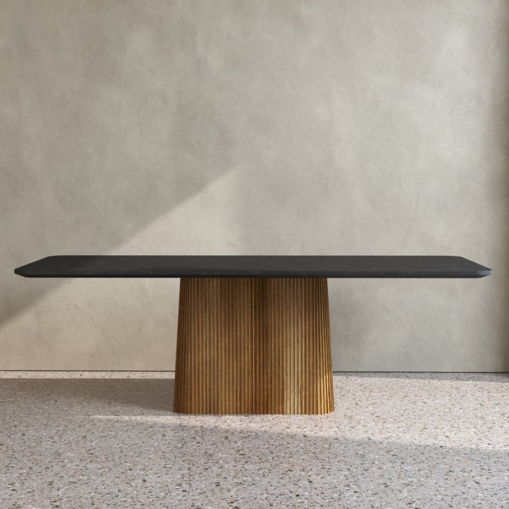An Osaka Dining Table, featuring a modern black rectangular top and a ribbed wooden pedestal base, is placed against a light-colored wall on a terrazzo floor.