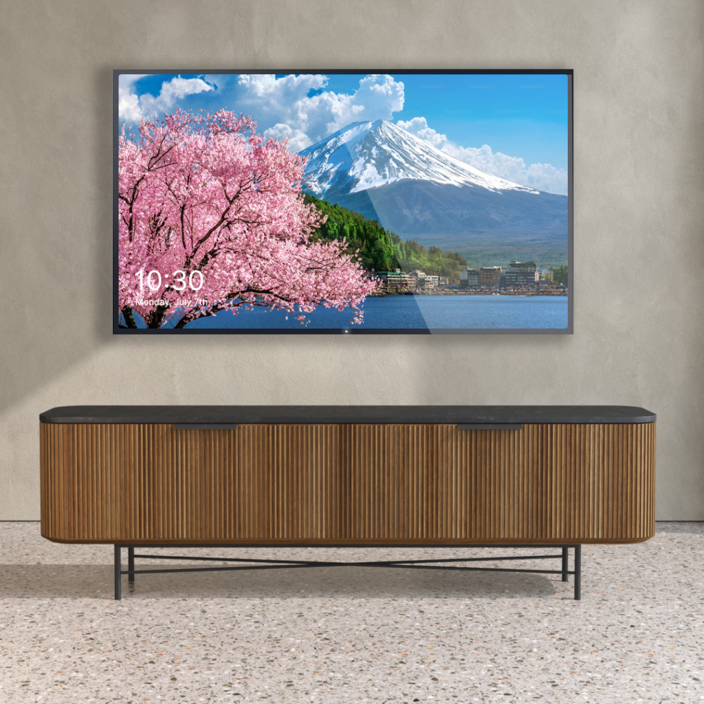 A television mounted on a gray wall displays an image of a mountain, cherry blossoms, and a lake. The Osaka Wide TV Stand sits below on the terrazzo floor. The TV screen shows the time as 10:30.