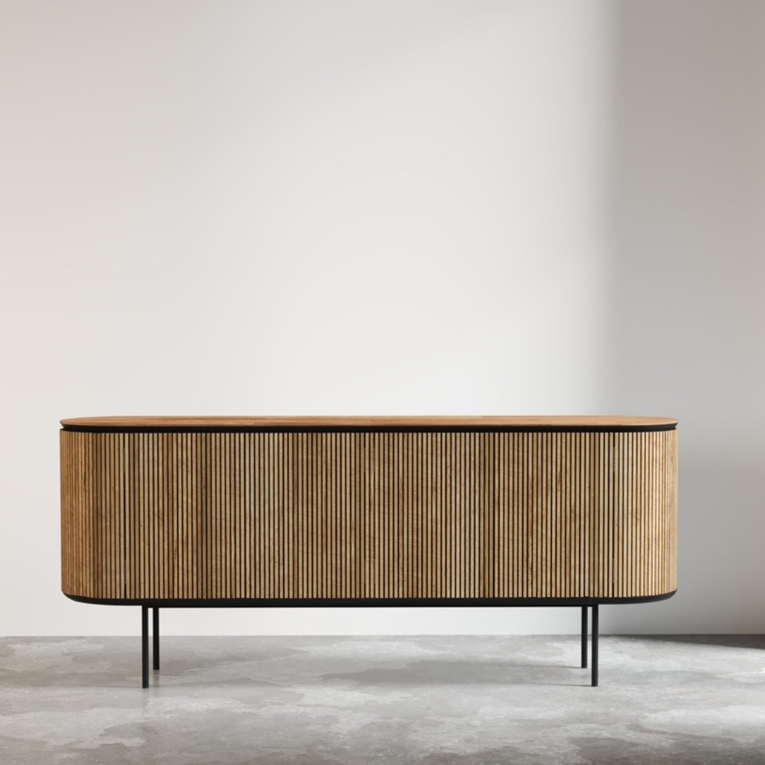Untitled-design-1.jpg The Bolivar Dining Buffet, a modern wooden sideboard featuring vertical slats and black metal legs, stands against a plain white wall on a concrete floor.