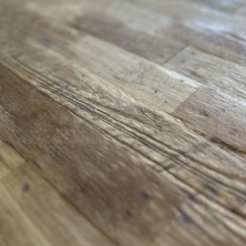 A close-up of the Metal Dining Table (Natural) highlights its textured surface, unique grain-inspired details, and subtle imperfections, with the background softly blurred for emphasis.