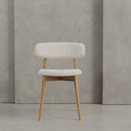 The Alto 20" Dining Chair (Wood) features light wood legs and a white upholstered seat and backrest, shown against a textured gray wall and floor.