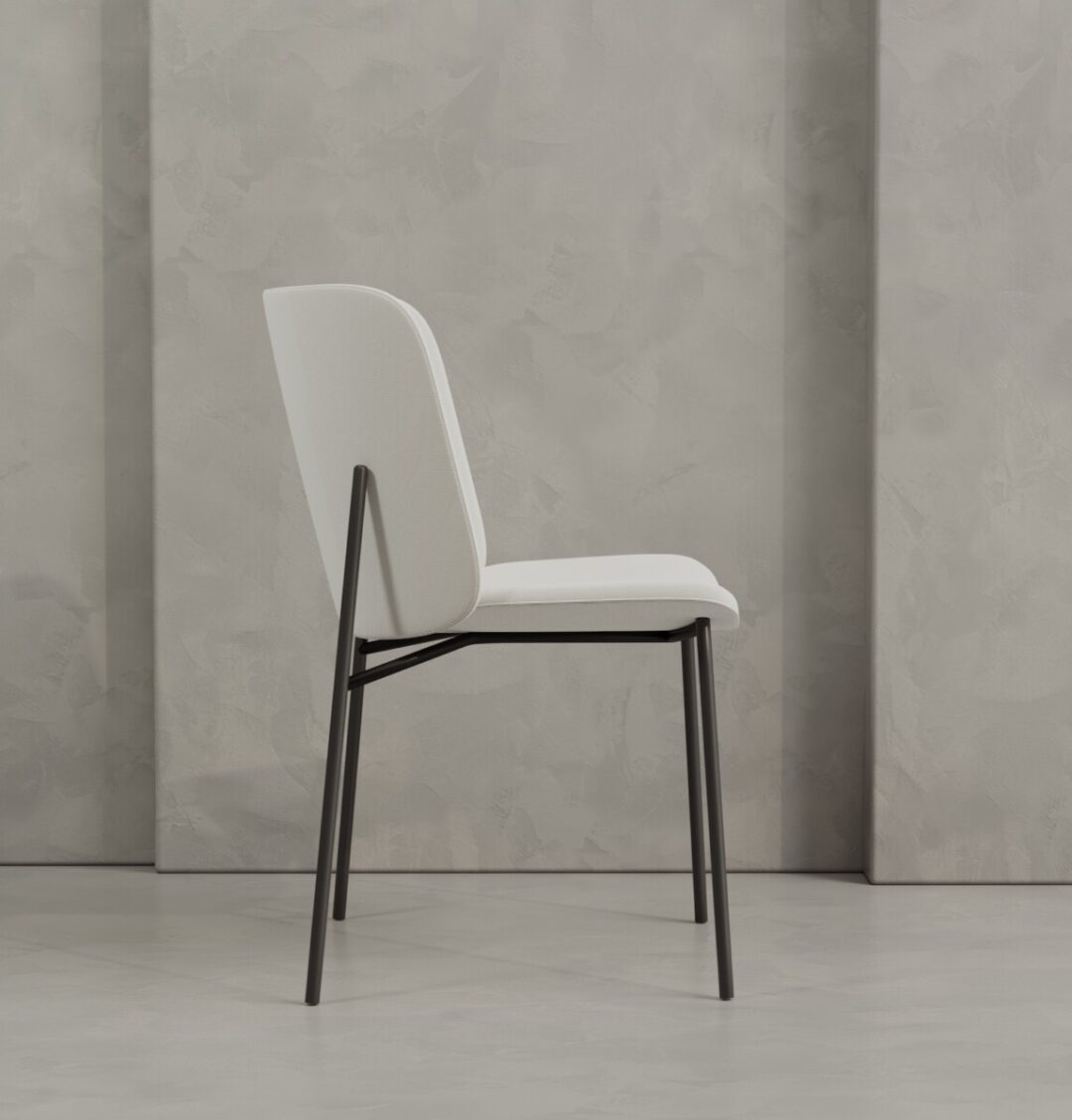 2 Kora The Kora 20" Dining Chair, featuring modern white upholstery and a black metal frame, sits on a light gray floor against a textured gray wall.