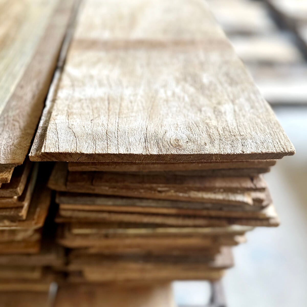 A close-up view of stacked wooden planks, highlighting their rough texture and natural grain pattern.