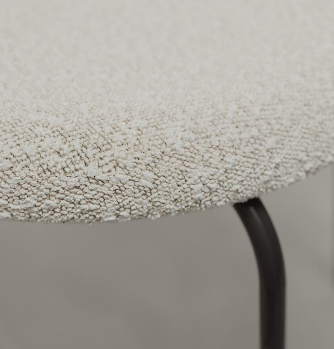 4 Alto Metal Close-up of the Alto 20" Dining Chair (Metal), featuring a round, textured, off-white upholstered seat and black metal legs.