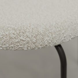 Close-up of the Alto 20" Dining Chair (Metal), featuring a round, textured, off-white upholstered seat and black metal legs.