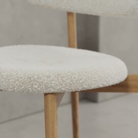 Close-up of the Alto 20" Dining Chair (Wood) featuring a wooden frame with a round, textured off-white upholstered seat and backrest.