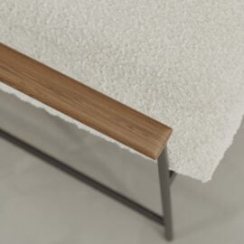 Close-up of the Aspen 30" Lounge Chair featuring a textured white cushion, wooden armrest, and black metal frame on a light-colored floor.