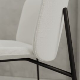 Close-up of the Kora 20" Dining Chair, featuring a textured white seat and backrest with a black metal frame, set against a light gray background.