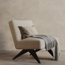 The Laurel 27" Lounge Chair, upholstered in beige with dark angled legs, includes a gray patterned throw and taupe pillow, set against a textured neutral wall.