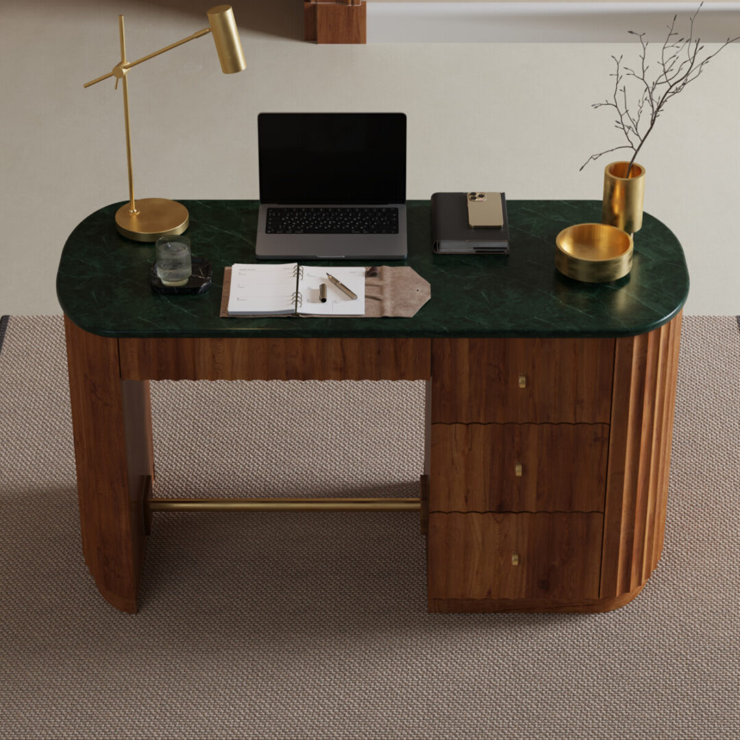 Elma 53-in. Desk-03 The Elma Desk, featuring a green marble top and three drawers, stands on a beige carpet and holds a laptop, lamp, glass of water, notebook, tray, gold bowl, and a vase with twigs.