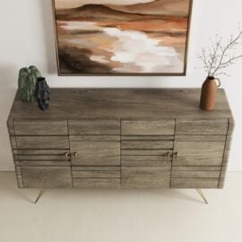 The Kava Sideboard, featuring four doors, is decorated with two vases and a bare branch, and sits below a landscape painting in earthy tones.