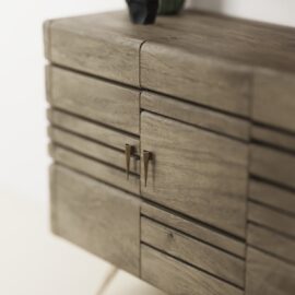 A close-up view of the Kava Sideboard shows its textured wooden surface and two metal handles on the front doors.