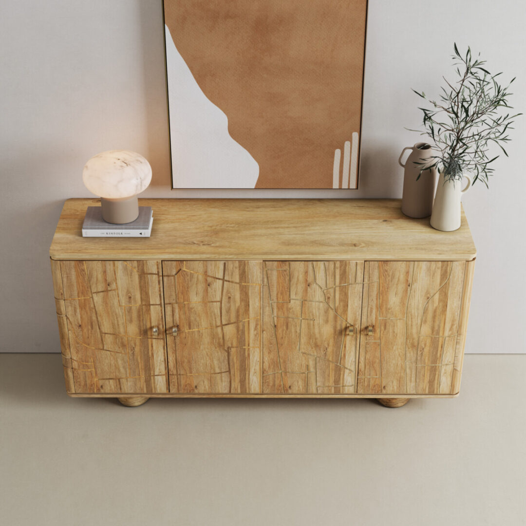 Noka 60-in. Sideboard-03 The Noka Sideboard features textured doors and is styled with a marble lamp, a stack of books, a ceramic vase with greenery, and abstract wall art above.
