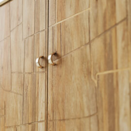 Close-up of the Noka Sideboard’s wooden cabinet doors showcasing natural grain and two metallic handles.