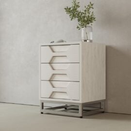 The Vexa Nightstand features a modern, light wood design with three geometric drawers, a metal base, and is topped with a clear vase of green foliage against a plain light-colored wall.