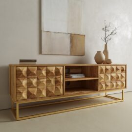 The Wadi TV Stand, featuring geometric patterns and open shelves, is set against a beige wall with books, ceramic vases, and a minimalist branch displayed on top. Abstract art hangs above.
