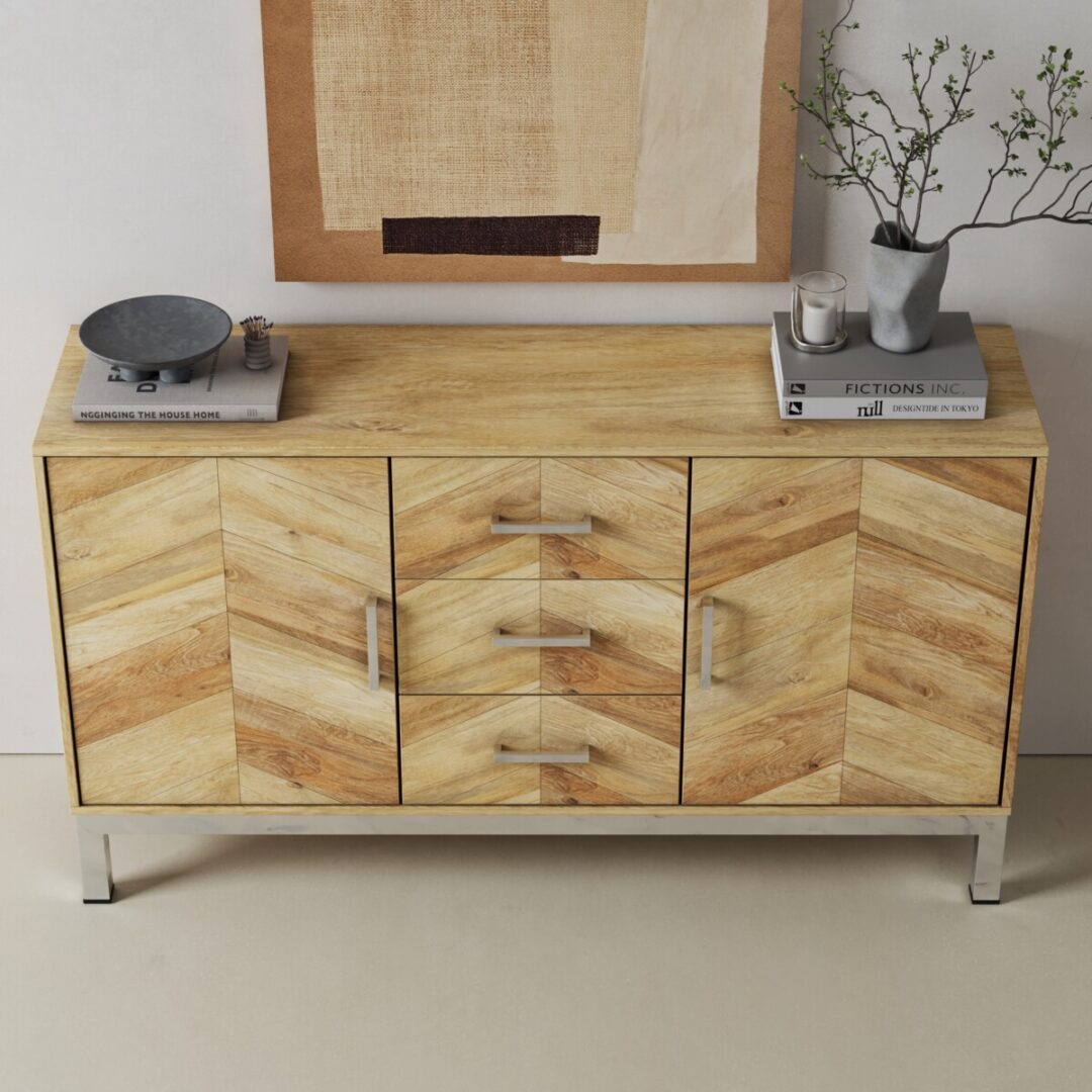 Zera 56in. Sideboard-04 The Zera Sideboard features a wooden chevron pattern, metal legs and handles, and is styled with a scale, books, and a vase with branches. It sits against a wall adorned with abstract art.