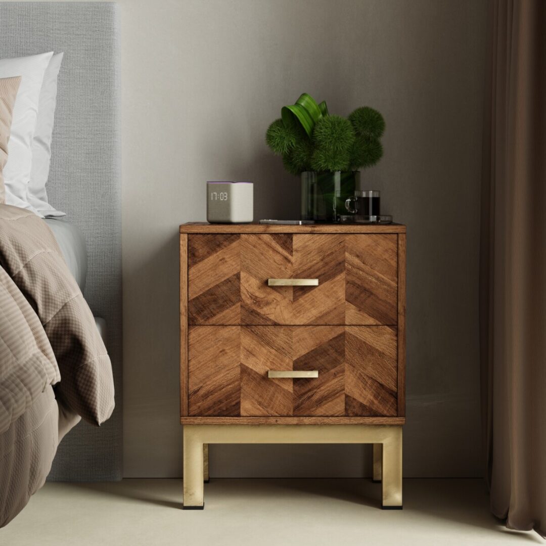 The Zera Sideboard with two drawers and gold handles sits beside a bed. On top are a digital clock, a glass of water, and a vase with green decorative plants.
