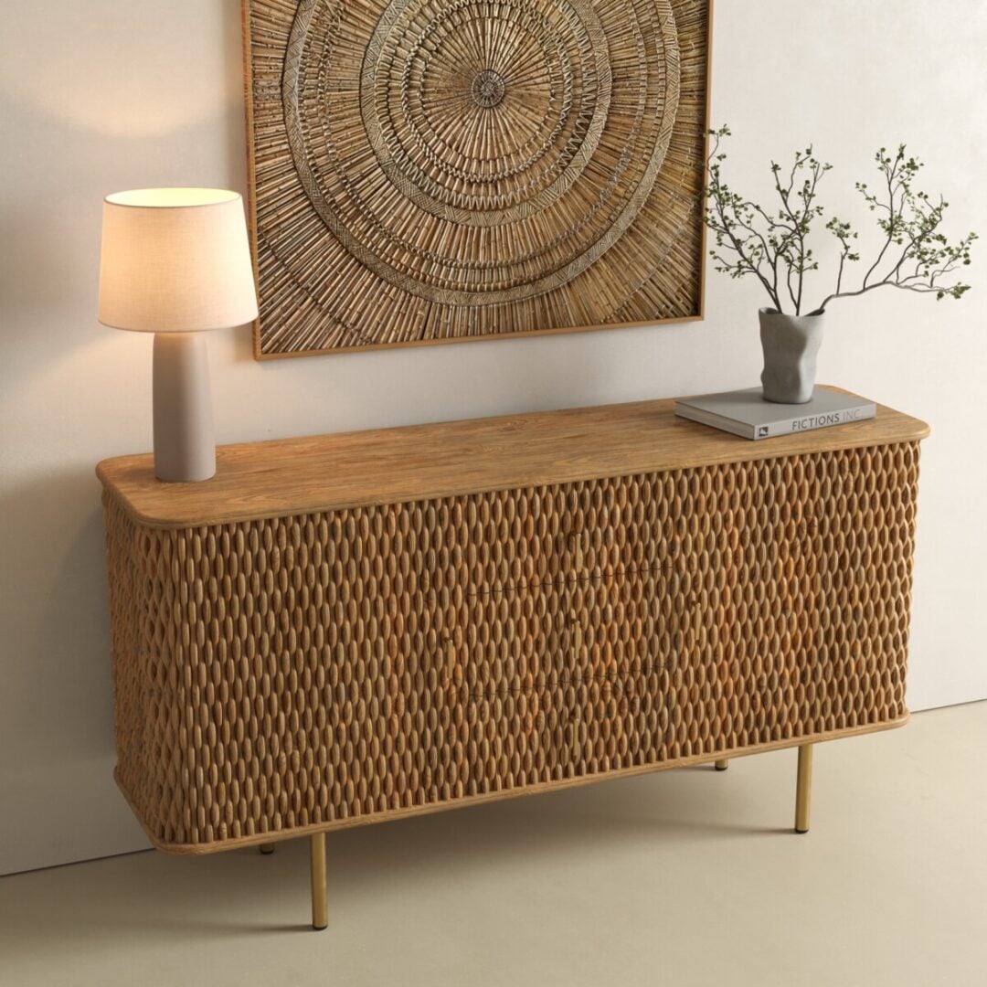 Salaro 60in Sideboard-03 A wooden sideboard with a textured front, a lamp, a gray vase with branches, and a book placed on top, beneath a circular woven wall art.